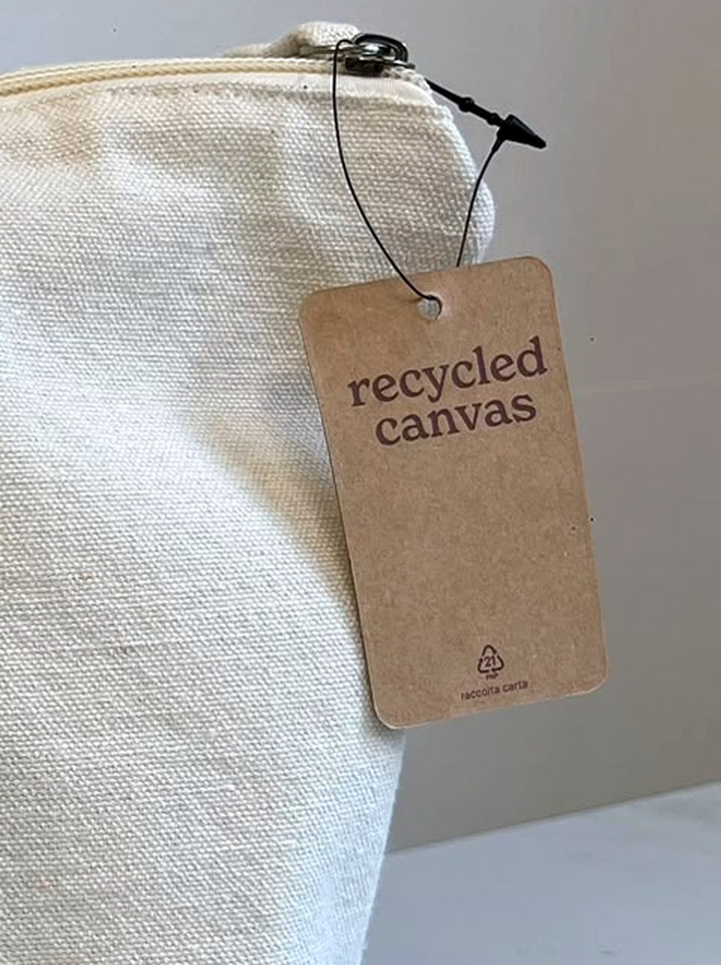 Etichetta in cartoncino riciclato "recycled canvas" appesa alla zip della pochette Mamata